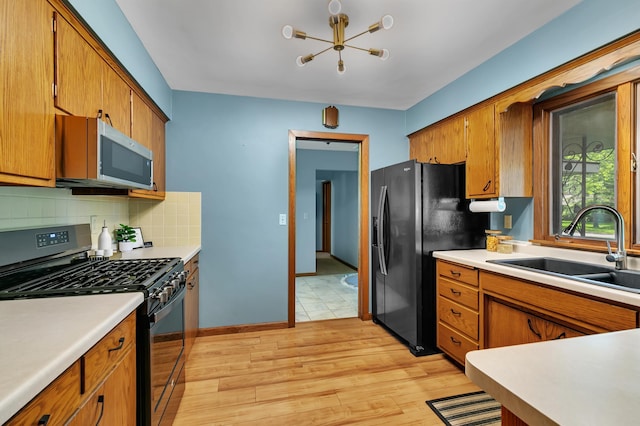 5843 Fairway Ln, Saint Cloud, MN 56303 - kitchen featuring black appliances, a sink, a chandelier, and brown cabinetry