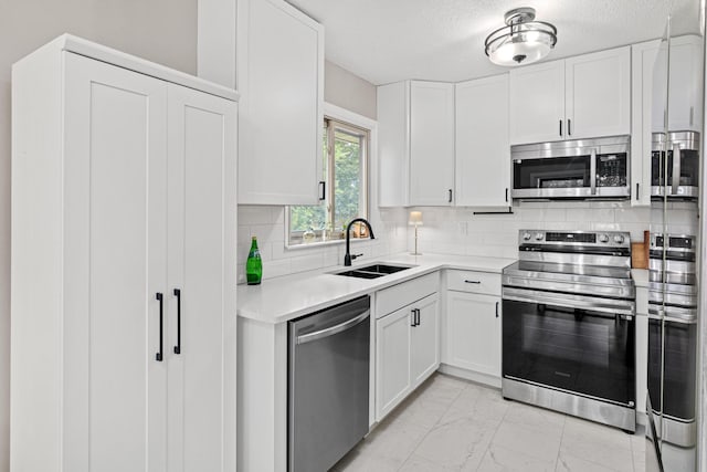 2613 107th Ln NW, Coon Rapids, MN 55433 - kitchen featuring appliances with stainless steel finishes, light marble finish flooring, light countertops, white cabinetry, and tasteful backsplash