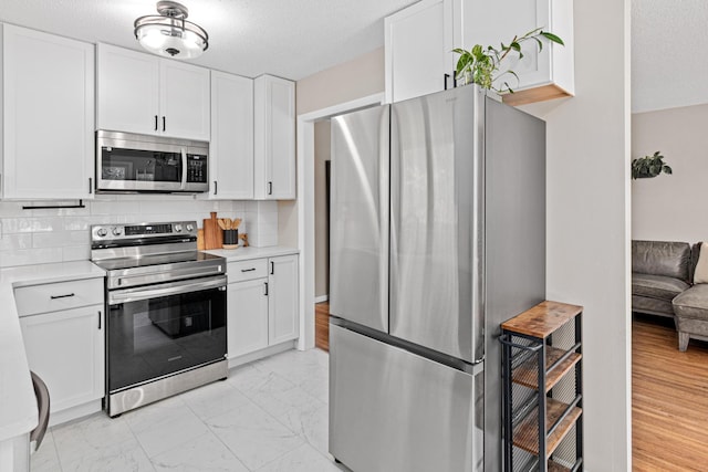 2613 107th Ln NW, Coon Rapids, MN 55433 - kitchen featuring appliances with stainless steel finishes, light countertops, light marble finish flooring, white cabinetry, and decorative backsplash