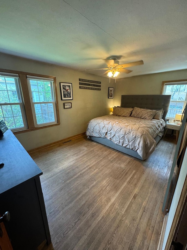 41 17th Ave N, Hopkins, MN 55343 - bedroom featuring multiple windows, wood finished floors, baseboards, ceiling fan, and a textured ceiling