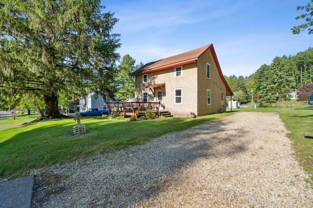 S233 Church Ave, Spring Valley, WI 54767 - view of side of home with gravel driveway, a wooden deck, stucco siding, and a yard
