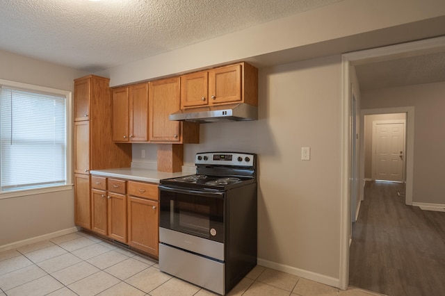 922 Minnehaha Ave E, Saint Paul, MN 55106 - kitchen featuring stainless steel range with electric stovetop, under cabinet range hood, light countertops, a textured ceiling, and baseboards