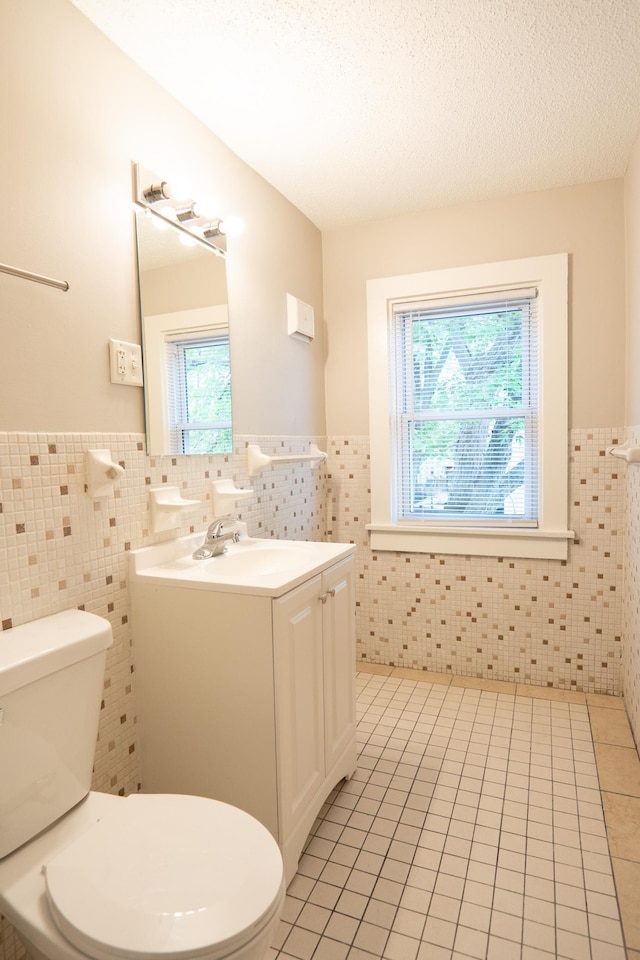 922 Minnehaha Ave E, Saint Paul, MN 55106 - half bathroom featuring tile walls, toilet, a wainscoted wall, tile patterned flooring, and vanity