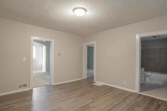 922 Minnehaha Ave E, Saint Paul, MN 55106 - unfurnished room featuring wood finished floors, arched walkways, a textured ceiling, and baseboards