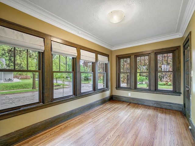 1715 Bush Ave, Saint Paul, MN 55106 - unfurnished sunroom featuring plenty of natural light, baseboards, ornamental molding, wood finished floors, and a textured ceiling