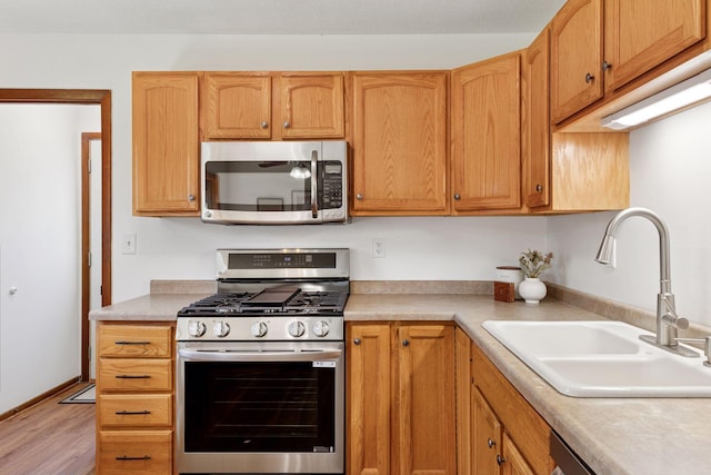 11124 Welcome Ave N, Champlin, MN 55316 - kitchen with appliances with stainless steel finishes, a sink, light wood-style flooring, and light countertops
