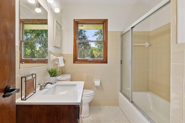 11124 Welcome Ave N, Champlin, MN 55316 - bathroom featuring tile walls, toilet, vanity, shower / bath combination with glass door, and tile patterned flooring
