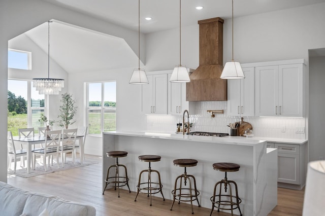 2520 230th Ct NW, Saint Francis, MN 55070 - kitchen with backsplash, a center island with sink, light wood-type flooring, custom range hood, and high vaulted ceiling