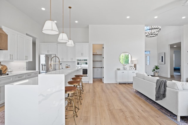 2520 230th Ct NW, Saint Francis, MN 55070 - kitchen with a towering ceiling, stainless steel appliances, open floor plan, light wood-style floors, and white cabinetry