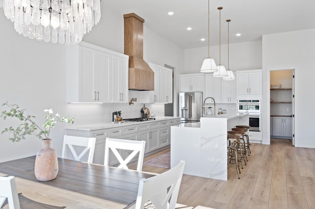 2520 230th Ct NW, Saint Francis, MN 55070 - kitchen featuring appliances with stainless steel finishes, custom range hood, tasteful backsplash, white cabinets, and a breakfast bar
