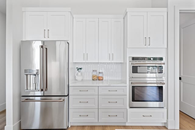 2520 230th Ct NW, Saint Francis, MN 55070 - kitchen featuring stainless steel appliances, white cabinetry, backsplash, and light wood finished floors