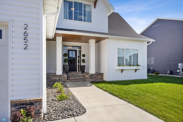 2652 70th Ave S, Fargo, ND 58104 - view of exterior entry with a lawn, a shingled roof, and board and batten siding