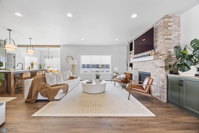 2652 70th Ave S, Fargo, ND 58104 - living room with healthy amount of natural light, a brick fireplace, wood finished floors, recessed lighting, and a chandelier