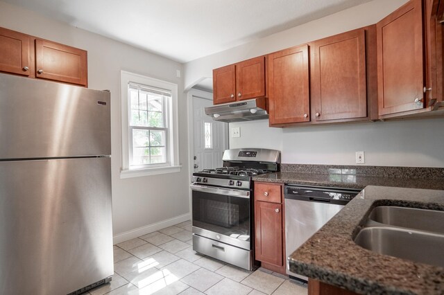 3550 Bryant Ave N, Minneapolis, MN 55412 - kitchen featuring stainless steel appliances, under cabinet range hood, brown cabinets, light tile patterned floors, and baseboards