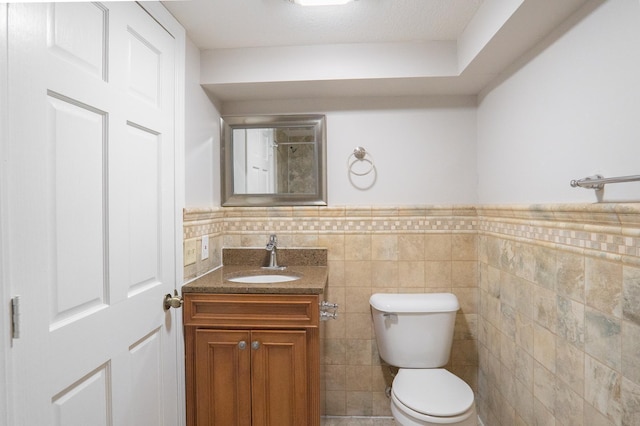 3550 Bryant Ave N, Minneapolis, MN 55412 - bathroom featuring toilet, vanity, tile walls, and a wainscoted wall
