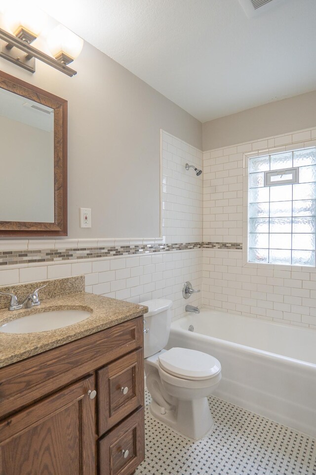 3550 Bryant Ave N, Minneapolis, MN 55412 - full bath featuring tile walls, vanity, toilet, shower / bathtub combination, and a wainscoted wall