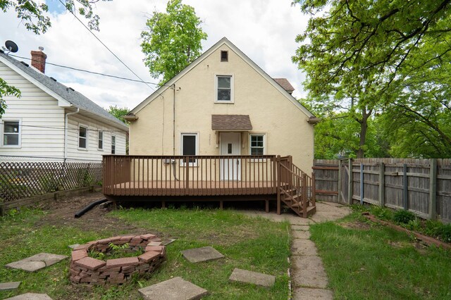 3550 Bryant Ave N, Minneapolis, MN 55412 - back of property featuring stucco siding, a wooden deck, a fenced backyard, and a fire pit