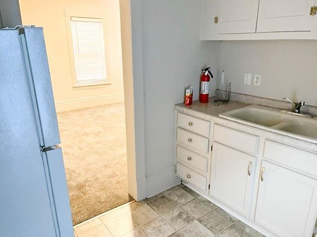 310 Burgess St, Saint Paul, MN 55117 - kitchen with freestanding refrigerator, light carpet, a sink, white cabinets, and light countertops