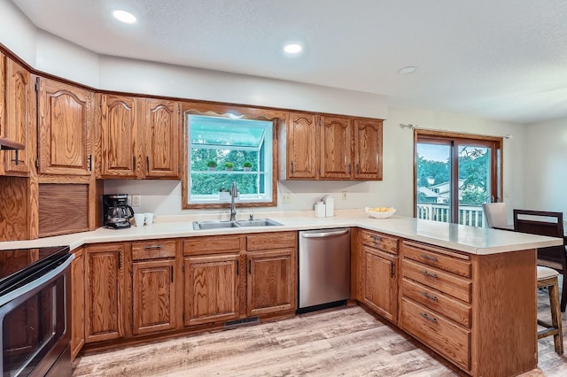 4900 Hodgson Rd, Connection, Shoreview, MN 55126 - kitchen featuring appliances with stainless steel finishes, a peninsula, brown cabinetry, light wood-style flooring, and recessed lighting
