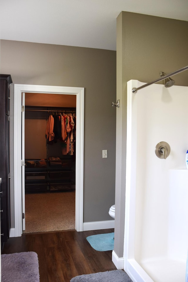 2008 Whiting Rd NW Unit 10, Bemidji, MN 56601 - bathroom featuring a shower, wood finished floors, toilet, a walk in closet, and baseboards