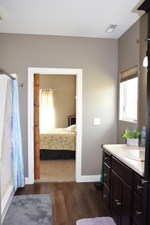2008 Whiting Rd NW Unit 10, Bemidji, MN 56601 - bathroom featuring wood finished floors, connected bathroom, vanity, baseboards, and curtained shower