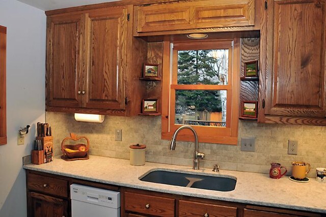 29626 436th Pl, Farm Island Twp, MN 56431 - kitchen featuring dishwasher, a sink, decorative backsplash, light stone counters, and brown cabinets