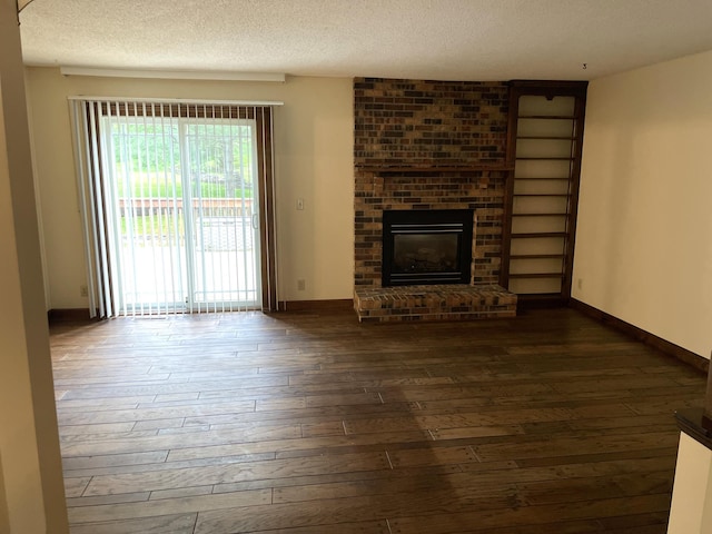 7765 Woodpark Blvd, Woodbury, MN 55125 - unfurnished living room with dark wood-type flooring, a textured ceiling, a brick fireplace, and baseboards