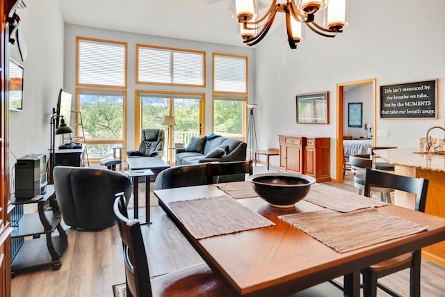 1439 Summit Shores Dr, Burnsville, MN 55306 - dining space featuring a towering ceiling, a chandelier, and light wood-type flooring
