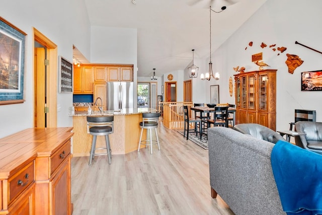 1439 Summit Shores Dr, Burnsville, MN 55306 - kitchen featuring stainless steel refrigerator, light wood finished floors, a breakfast bar, high vaulted ceiling, and open floor plan