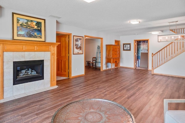 1439 Summit Shores Dr, Burnsville, MN 55306 - unfurnished living room featuring wood finished floors, a textured ceiling, baseboards, a tiled fireplace, and stairway