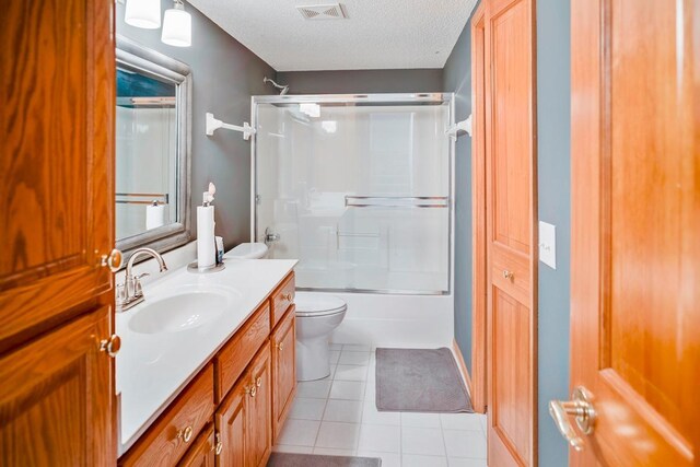 1439 Summit Shores Dr, Burnsville, MN 55306 - bathroom with vanity, toilet, tile patterned floors, shower / bath combination with glass door, and a textured ceiling
