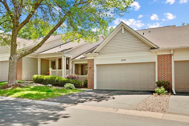 1439 Summit Shores Dr, Burnsville, MN 55306 - view of front facade with brick siding, a garage, a porch, a shingled roof, and driveway
