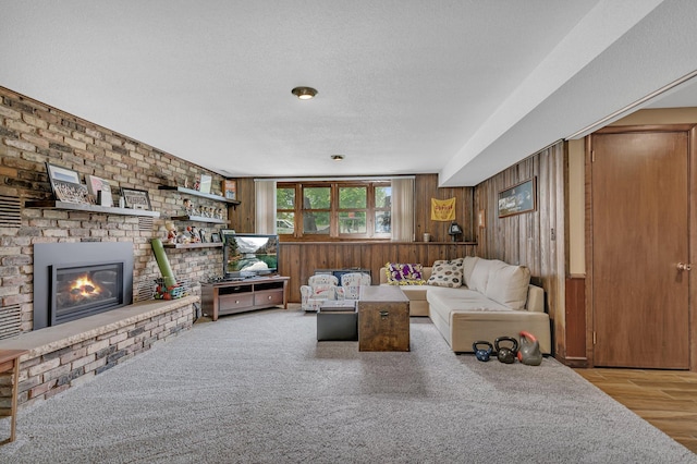 303 Park Ave SE, Pierz, MN 56364 - living area featuring wooden walls, a brick fireplace, wood finished floors, and a textured ceiling