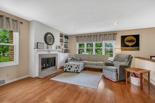 303 Park Ave SE, Pierz, MN 56364 - living room featuring wood finished floors, baseboards, a tiled fireplace, and recessed lighting