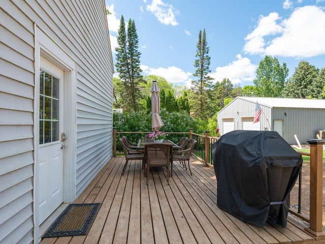 306 Benton St W, Cologne, MN 55322 - wooden terrace featuring outdoor dining area, a garage, area for grilling, an outdoor structure, and view of wooded area
