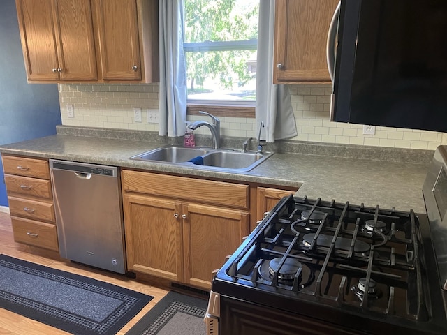 408 Beech Ave, Fergus Falls, MN 56537 - kitchen featuring stainless steel dishwasher, black gas range oven, a sink, tasteful backsplash, and dark countertops