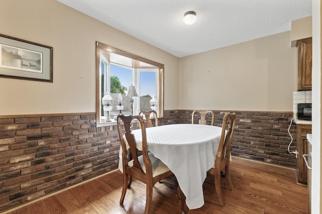 8847 Ironwood Ave S, Cottage Grove, MN 55016 - dining space featuring brick wall, wainscoting, and wood finished floors