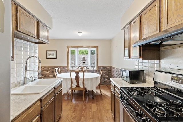 8847 Ironwood Ave S, Cottage Grove, MN 55016 - kitchen featuring gas range, a sink, black microwave, wainscoting, and ventilation hood