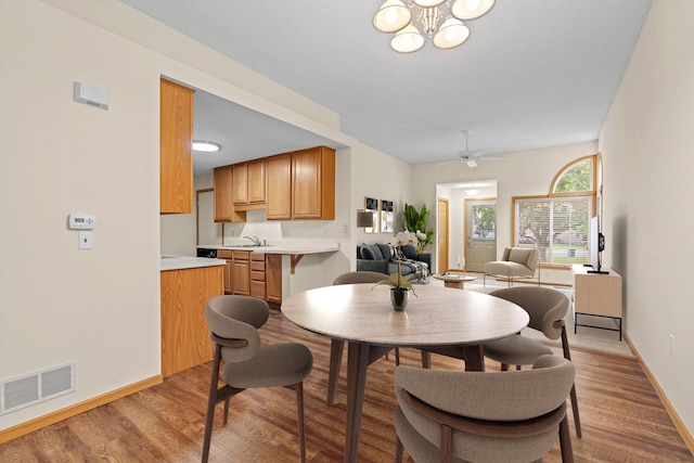 10767 Tamarack Cir NW, Coon Rapids, MN 55433 - dining area featuring light wood finished floors, a ceiling fan, and a chandelier