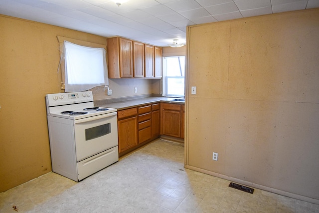 715 8th St E, Thief River Falls, MN 56701 - kitchen with white electric range, light floors, brown cabinets, and light countertops