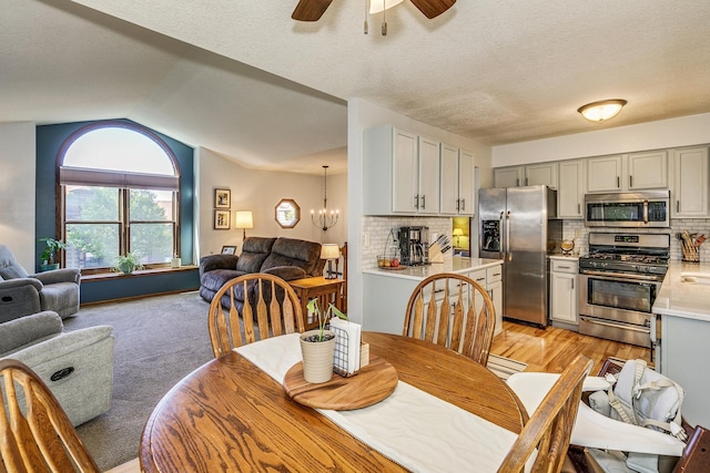 3948 Orchid Ln N, Plymouth, MN 55446 - dining area with vaulted ceiling, a chandelier, a ceiling fan, a textured ceiling, and light colored carpet
