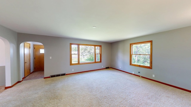 706 19th St, Albert Lea, MN 56007 - empty room featuring arched walkways, healthy amount of natural light, baseboards, and light colored carpet