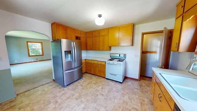 706 19th St, Albert Lea, MN 56007 - kitchen with stainless steel fridge, white range with gas cooktop, a sink, light countertops, and brown cabinets