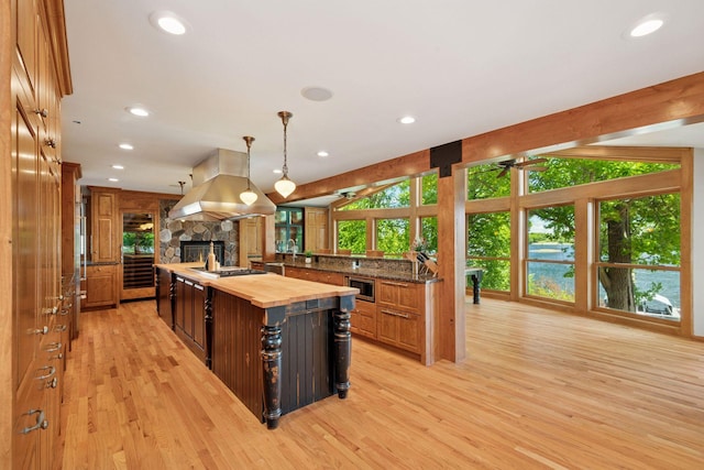 4080 Lotus Dr, Minnetrista, MN 55331 - kitchen featuring butcher block countertops, stainless steel microwave, a stone fireplace, recessed lighting, and light wood-style floors