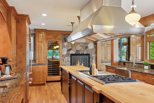 4080 Lotus Dr, Minnetrista, MN 55331 - kitchen featuring wood counters, island exhaust hood, stainless steel gas cooktop, a sink, and light wood finished floors