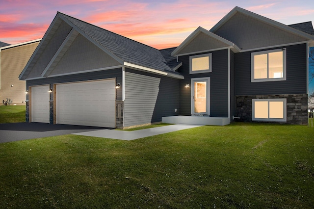 2135 Violet Ln, Faribault, MN 55021 - view of front facade with an attached garage, a front yard, stone siding, asphalt driveway, and a shingled roof