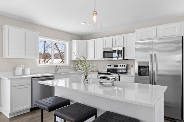 2135 Violet Ln, Faribault, MN 55021 - kitchen featuring stainless steel appliances, a sink, a kitchen bar, white cabinetry, and light countertops