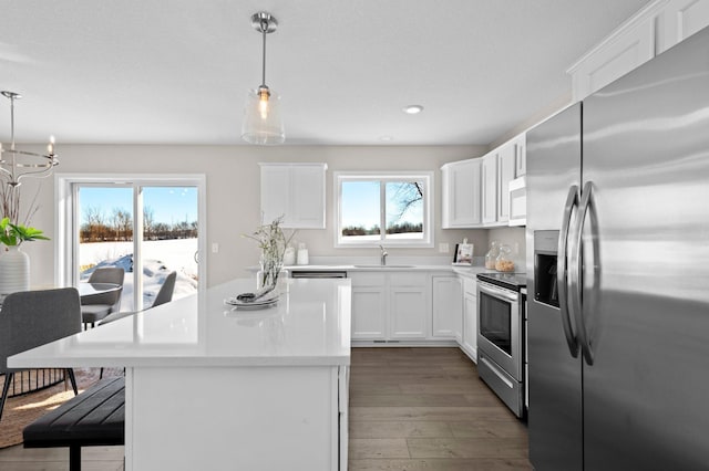 2135 Violet Ln, Faribault, MN 55021 - kitchen featuring stainless steel appliances, a sink, hardwood / wood-style flooring, a center island, and light countertops