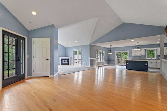 1901 Lexington Ave S, Mendota Heights, MN 55118 - unfurnished living room featuring a chandelier, a glass covered fireplace, light wood-style floors, high vaulted ceiling, and healthy amount of natural light