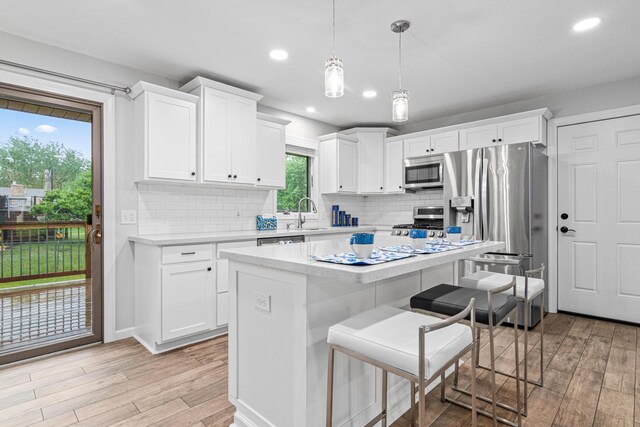 11508 Georgia Ave N, Champlin, MN 55316 - kitchen with stainless steel appliances, light wood-type flooring, a kitchen breakfast bar, light countertops, and tasteful backsplash